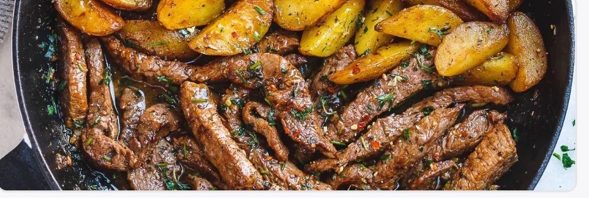 Skillet of seared steak strips and roasted potato wedges — the recipe photo from the live product
